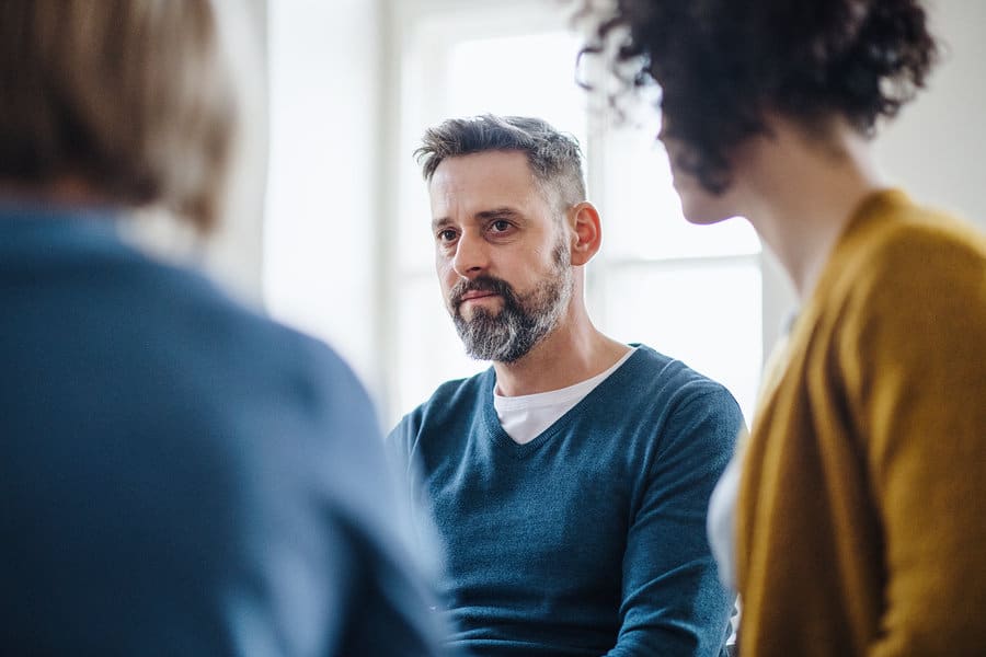 Focus shot of a man sitting a group with two other people