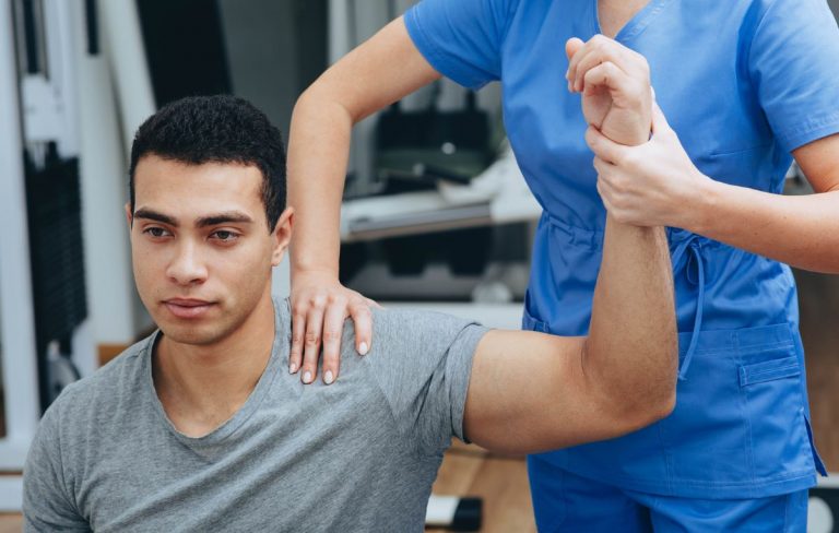 A professional athlete getting shoulder rehab from a physical therapist.