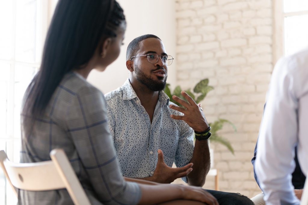 A man opening up about his struggle with addiction in a group therapy session.