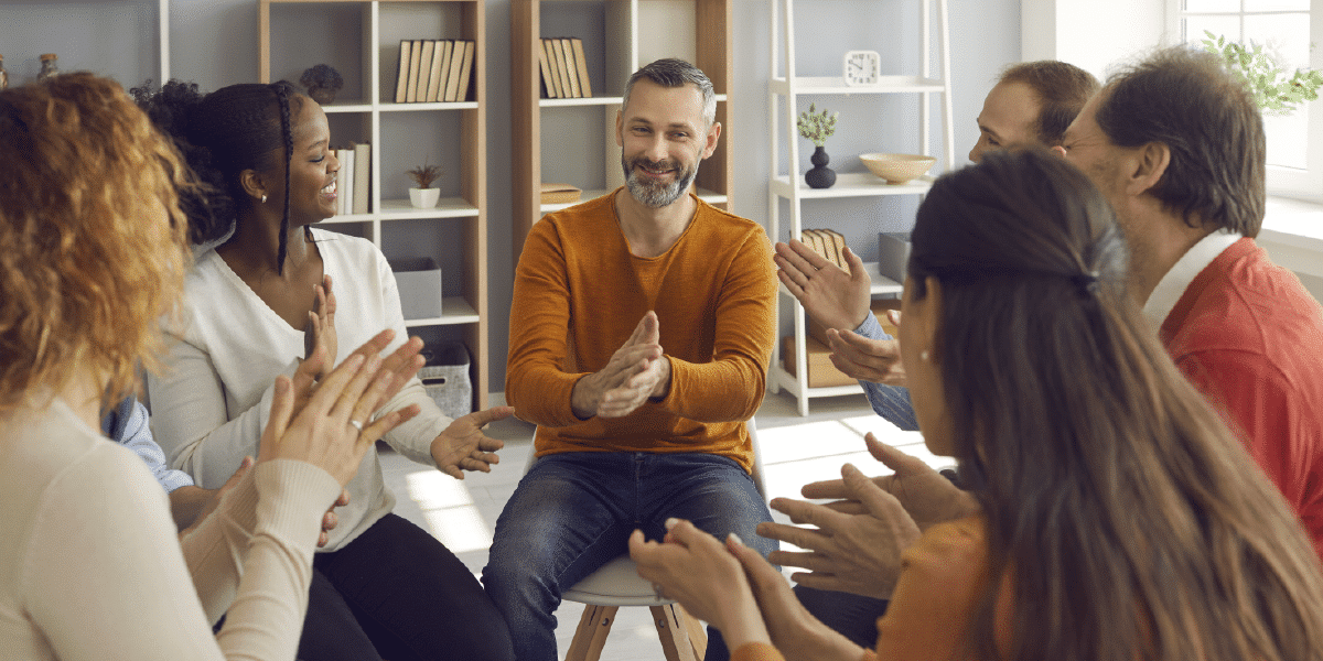 People sitting in a circle, applauding.
